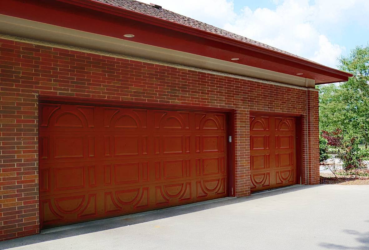 Brick house with two red garage doors in differnet sizes